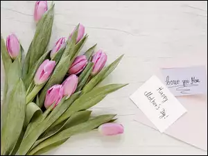Kartki z życzeniami dla mamy na deskach obok bukietu tulipanów