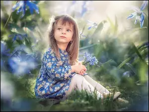 Dziewczynka na łące pośródniebieskich kwiatów cybulicy syberyjskiej