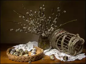 Bazie w wazonie obok jajeczek i wiklinowego koszyka