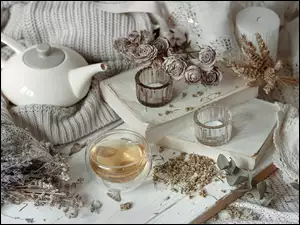 Czajnik i suszone kwiaty obok filiżankę herbaty i świece