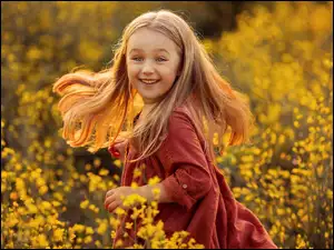 Uśmiechnięta dziewczyna na łące wśród kwiatów