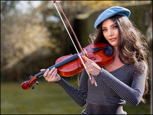 Długowłosa kobieta w niebieskim berecie ze skrzypcami