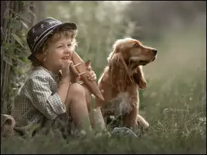 Chłopiec siedzący z psem w trawie