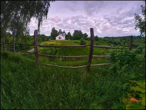 Ogrodzona łąka i droga do kościoła na wzgórzu