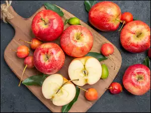 Jabłka i czereśnie na desce do krojenia