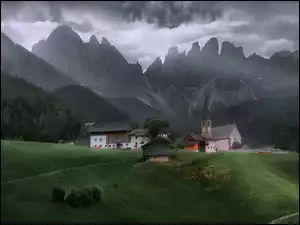Domy i kościół na tle Dolomitów we Włoszech