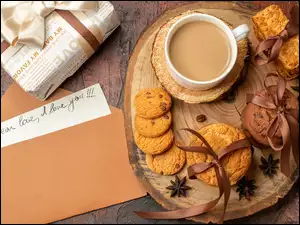List w kopercie i prezent obok ciastek i kawy na desce