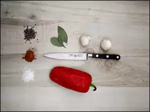 Przyprawy obok noża i czerwona papryka