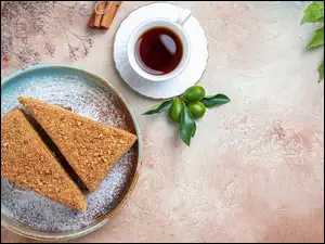 Kawa obok dwóch kawałków ciasta na talerzyku