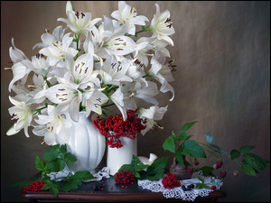 Białe lilie w wazonie obok owoców i kaliny