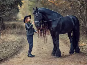 Dziewczynka z czarnym koniem na drodze