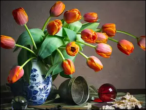 Czerwone tulipany w wazonie obok pucharu szklanych kul i muszli