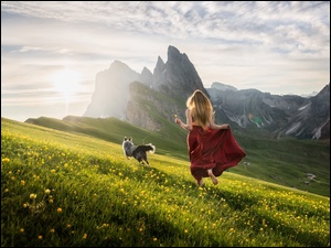 Dziewczyna z psem na łące na tle gór