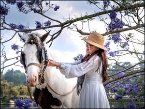 Dziewczyna trzymająca konia za uprząż