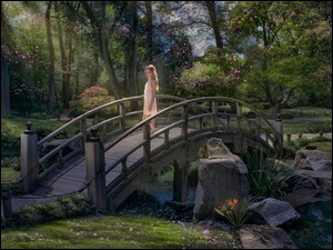 Kobieta na mostku nad strumieniem w wiosennym parku