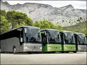 Cztery autobusy na placu na tle gór