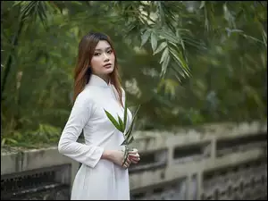 Azjatka w białej sukience przy płocie