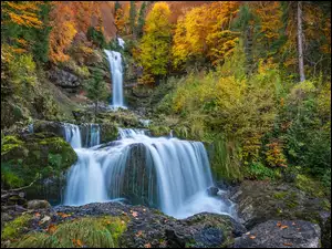 Wodospadspływający po skale w jesiennym lesie
