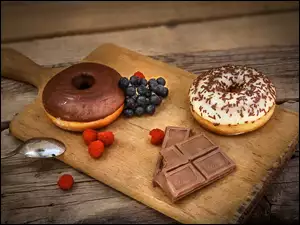 Na desce donuts z kawałkami czekolady i owocami
