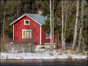 Czerwony domek nad ośnieżonym brzegiem rzeki