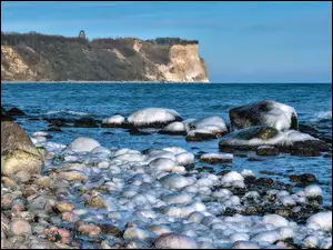 Śnieg na kamieniach na wybrzeżu morza