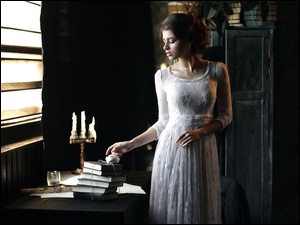 Kobieta w białej sukience przy stoliku z książkami