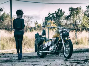 Kobieta z motocyklem na polnej drodze