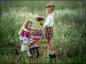 Dzieci z bukietami kwiatów na łące