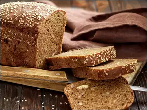 Bochenek chleba pokrojony na kromki i nóż