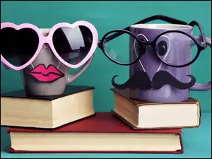 Śmieszne kubki w okularach stoją na książkach