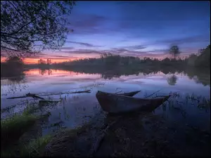Wieczorne niebo nad rzeką z łódką z drzewami
