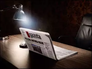 Lampka oświetlająca myszkę i gazetę ułożoną na kształt laptopa