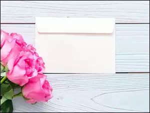 Róże obok koperty na deskach