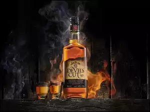 Butelka whisky z kieliszkami w dymie