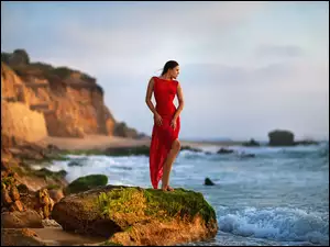 Kobieta w czerwonej sukience w sesji zdjęciowej na morskim urwisku