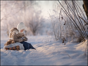 Chłopiec na sankach w śniegu