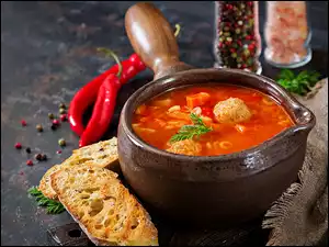Kromki chleba obok zupy pomidorowej z klopsikami