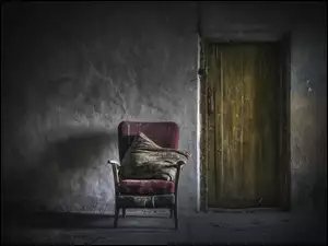 Stary zniszczony fotel obok drzwi w opuszczonym wnętrzu