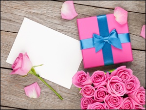 Różowe róże obok prezentu i kartki