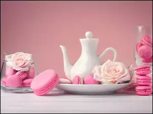 Różowy makaron i róże obok czajniczek