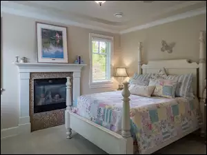 dziecięca sypialnia z kolorową narzutą i lalką na stoliku oraz kominkiem