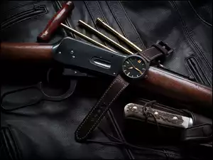 Karabin, nóż i zegarek położone na skórzanej kurtce