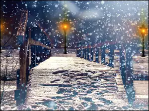 Most nad zamarzniętą rzeką w parku oświetlonym latarniami w prószącym śniegu