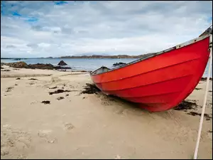Czerwona łódka zacumowana na plaży
