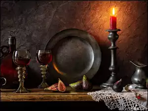 Cynowy talerz obok kieliszków i zapalonej świecy