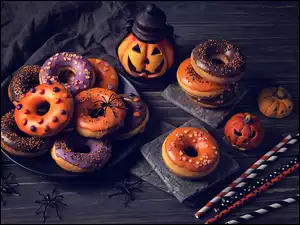 Donuty z lukrem obok wyciętych dyń na święto Halloween