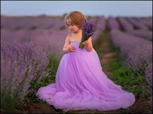 Dziewczynka w tiulowej sukience z bukietem na polu lawendy