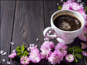 Filiżanka kawy i różowe kwiaty na desce