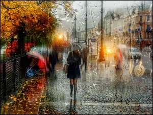 Kobieta pod parasolem na chodniku w deszczu