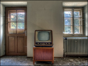 Stary telewizor na stoliku w zniszczonym pomieszczeniu z kaloryferem